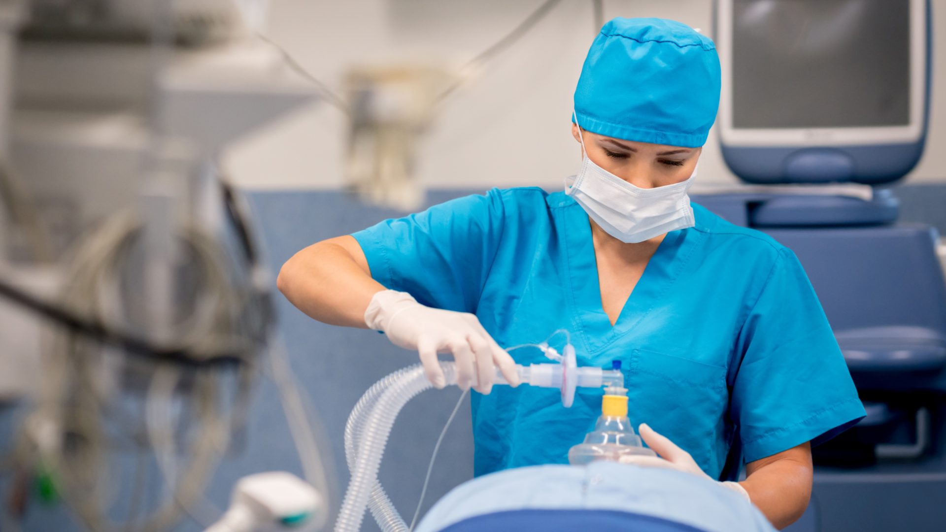 Nurse placing an oxygen mask on a patient during surgery in a hospital operating room