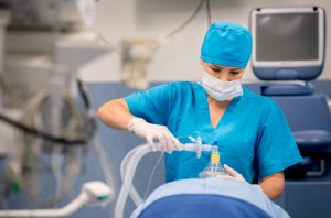 Nurse placing an oxygen mask on a patient during surgery in a hospital operating room