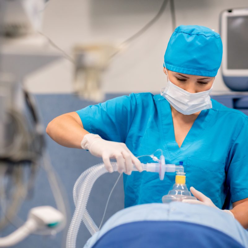 Nurse placing an oxygen mask on a patient during surgery in a hospital operating room